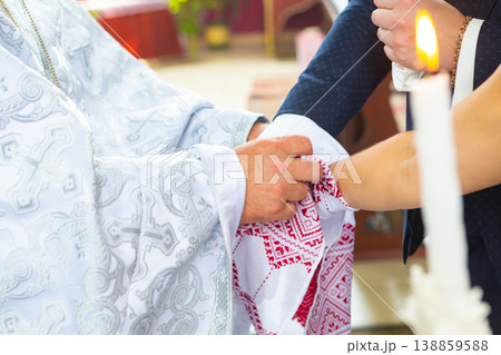 traditional Ukrainian Christian Wedding. the priest tied his hands to the newlyweds with a wedding towel on church. 138859588