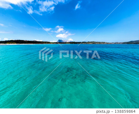 Low angle view of turquoise water at Lu Impostu beach with Tavolara island and cloudy blue sky 138859864