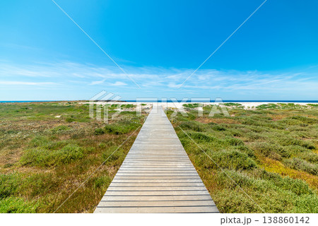 Wooden Boardwalk Leading to White Sand Beach under Blue Sky in Spring, Sardinia Wooden Boardwalk Leading to White Sand Beach under Blue Sky in Spring, Sardinia 138860142