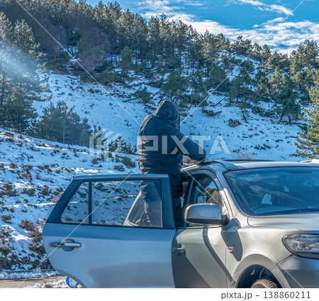 Man Standing on SUV Running Board Viewing Snow Covered Hill Partial SUV Visible Seen from Behind Man Standing on SUV Running Board Viewing Snow Covered Hill Partial SUV Visible Seen from Behind 138860211