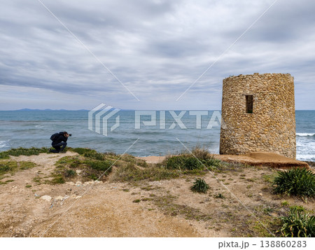Photographer Crouching to Capture Observation Tower by the Sea under Dramatic Gray Sky 138860283