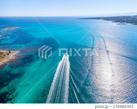 Aerial view of a motorboat leaving a white wake in the blue sea under a clear sky Aerial view of a motorboat leaving a white wake in the blue sea under a clear sky 138860303