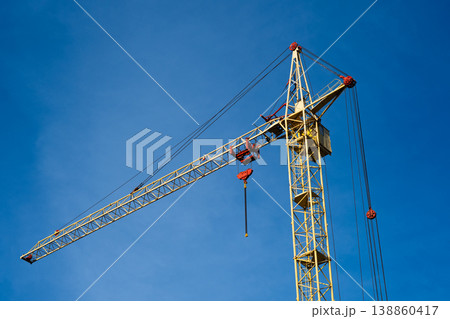 Yellow construction crane against the background of clear blue sky. 138860417