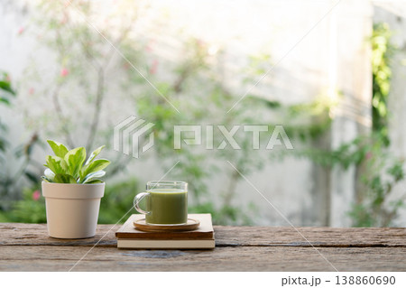 Matcha in a glass cup and notebook and plant on rustic brown table 138860690