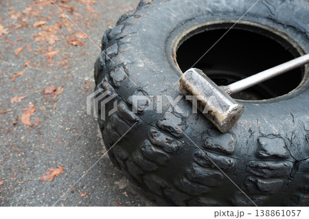 Wheel and metal sledgehammer for outdoors training . Developing strength, speed and endurance for an athlete Wheel and metal sledgehammer for outdoors training . Developing strength, speed and endurance for an athlete 138861057