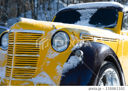 Close up view of an yellow and black retro car against the backdrop of a winter forest 138861102