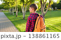 Happy child boy outdoors walks along park path at sunset. Schoolboy boy with backpack smiles. Happy child goes to school. Joyful kid outdoors enjoying nature, golden sunlight, and peaceful walk. 138861165