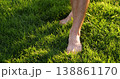 Bare feet walking on grass step softly across sunlit lawn. Barefoot steps press into blades and leave small impressions. Sunlit feet catch golden highlights. mood is peaceful and grounding. 138861170