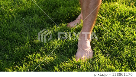 Bare feet walking on grass step softly across sunlit lawn. Barefoot steps press into blades and leave small impressions. Sunlit feet catch golden highlights. mood is peaceful and grounding. Bare feet walking on grass step softly across sunlit lawn. Barefoot steps press into blades and leave small impressions. Sunlit feet catch golden highlights. mood is peaceful and grounding. 138861170