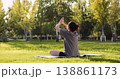 woman practices yoga outdoors on green grass at sunrise or sunset. Yoga outdoors brings woman peace, balance and awareness. Focused Zen woman meditating. Inspires peace and harmony in nature. 138861173
