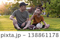 Happy father son relax on grass in park after playing ball. Joyful boy drinks water shares dad. Smiling father son enjoy sunset bonding outdoors. Family sport hydration healthy lifestyle golden hour. 138861178