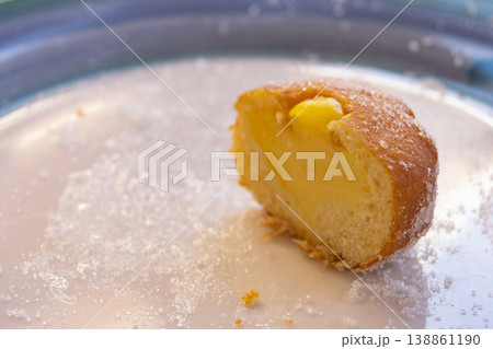Custard filled doughnut half with sugar on a white plate 138861190