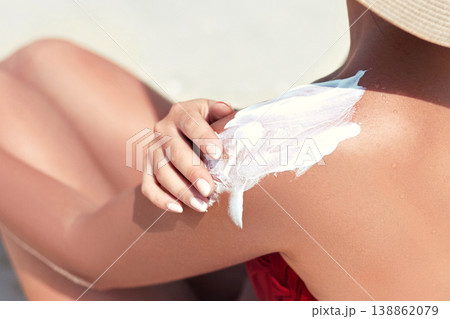 Woman applying sun protection on tanned back. Skincare. Body Sun protection suncream. Bikini hat woman applying moisturizing sunscreen lotion on back. 138862079