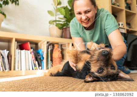 Woman playing with her pet dog on the carpet at home, enjoying a moment of companionship and happiness. Caring and loving pets. A happy moment in life 138862092