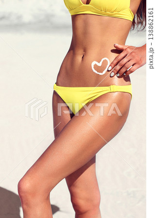 Woman with suntan lotion in form of the heart in yellow bikini Woman with suntan lotion in form of the heart in yellow bikini 138862161