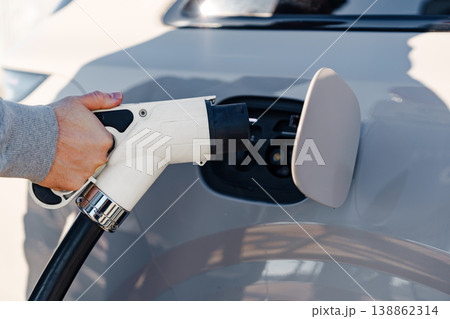 Charging an electric car at a public charging station during sunny weather Charging an electric car at a public charging station during sunny weather 138862314