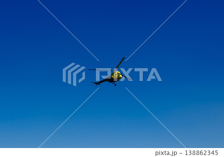 ellow rescue helicopter flying against deep clear blue sky with copy space at outdoor aviation airshow ellow rescue helicopter flying against deep clear blue sky with copy space at outdoor aviation airshow 138862345