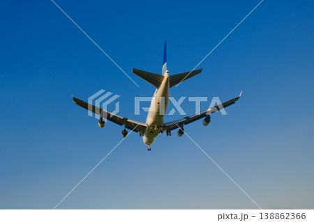 Large wide body commercial jet airplane flying against deep blue sky viewed from below at airfield Large wide body commercial jet airplane flying against deep blue sky viewed from below at airfield 138862366