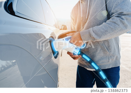 Person charging an electric car at a charging station during daylight 138862373