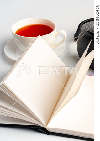 Tea and an open book with headphones on a table in a simple setting 138862466