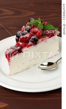 Delicious dessert slice on white plate with berries and mint on wooden table Delicious dessert slice on white plate with berries and mint on wooden table 138862474