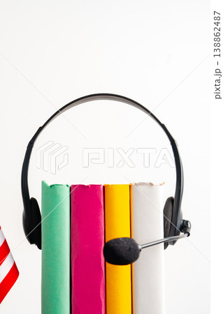 Headset sits above colorful books on a white background showing study or work setup 138862487