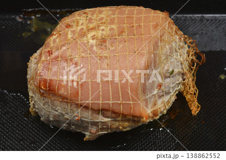 Pork roast in a net on a black baking tray Pork roast in a net on a black baking tray 138862552