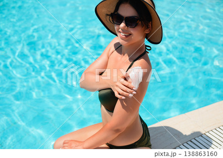Attractive Woman Applying Sunscreen On Shoulder Sitting Near Pool In Sunny Weather. Summer Skincare And Sun Protection Concept With Healthy Skin Glow Attractive Woman Applying Sunscreen On Shoulder Sitting Near Pool In Sunny Weather. Summer Skincare And Sun Protection Concept With Healthy Skin Glow 138863160