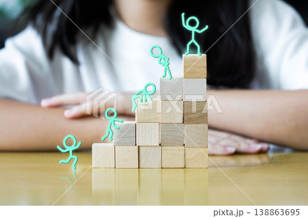 A child sits behind stacked wooden blocks shaped like rising steps. Simple stick figures suggest growth, progress, and steady achievement. 138863695
