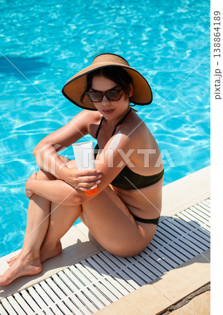 Woman Sitting By Poolside With Sunscreen On Shoulder Relaxing In Summer Sunlight And Enjoying Outdoor Lifestyle Woman Sitting By Poolside With Sunscreen On Shoulder Relaxing In Summer Sunlight And Enjoying Outdoor Lifestyle 138864189
