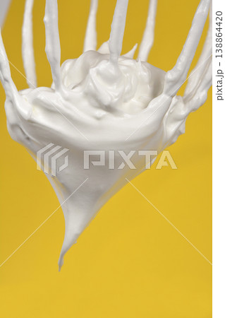 Meringue on a whisk over yellow background Meringue on a whisk over yellow background 138864420