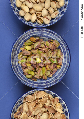 Pistachio varieties in blue bowls on blue background Pistachio varieties in blue bowls on blue background 138864560