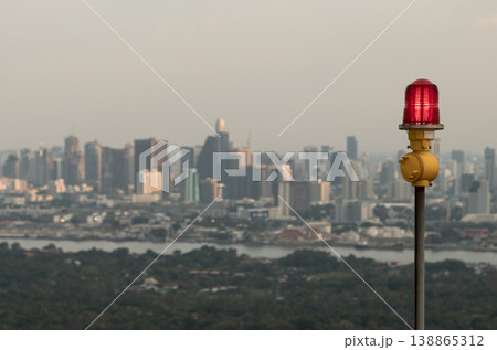 Standing as a solitary sentinel, a vibrant red obstruction light glows or aircraft warning light atop a slender yellow pole, its watchful radiance serving as a vital aeronautical beacon to ensure Standing as a solitary sentinel, a vibrant red obstruction light glows or aircraft warning light atop a slender yellow pole, its watchful radiance serving as a vital aeronautical beacon to ensure 138865312