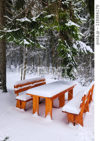 Wooden picnic table covered in fresh snow in forest 138866270