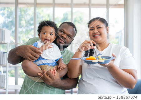 Happy family spending quality time feeding their baby in a bright home setting. Promotes healthy parenting, emotional bonding, and modern lifestyle through nurturing care and joyful interaction Happy family spending quality time feeding their baby in a bright home setting. Promotes healthy parenting, emotional bonding, and modern lifestyle through nurturing care and joyful interaction 138867074