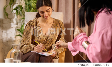 Close up of woman taking notes while business coach explains tasks during consultation 138869215