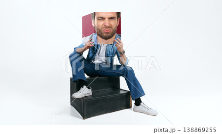 Man in casual denim outfit sitting on steps holding face print fashion portrait isolated background. Man in casual denim outfit sitting on steps holding face print fashion portrait isolated background. 138869255