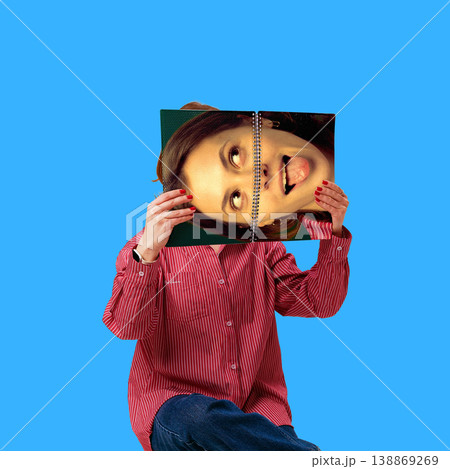 Woman holding notebook with printed face covering identity for social media content. Woman holding notebook with printed face covering identity for social media content. 138869269