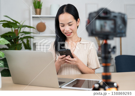 Content Creator Studio: A young woman, engaged in creating content, is seated at a table with a laptop, smartphone and camera, crafting a digital presence Content Creator Studio: A young woman, engaged in creating content, is seated at a table with a laptop, smartphone and camera, crafting a digital presence 138869293
