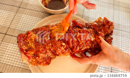 preparing marinated meat on a plate with sauce in a bowl nearby preparing marinated meat on a plate with sauce in a bowl nearby 138869759