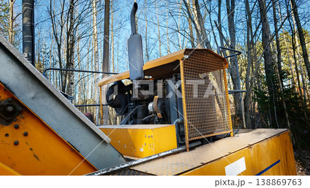 Yellow machine working in forest area with trees and clear sky Yellow machine working in forest area with trees and clear sky 138869763