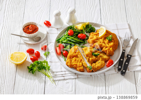 Breaded pork schnitzel with green beans and lemon Breaded pork schnitzel with green beans and lemon 138869859
