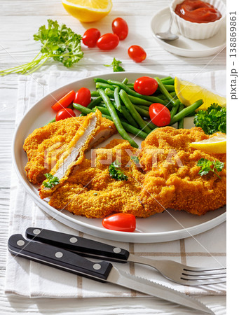 Breaded pork schnitzel with green beans and lemon 138869861