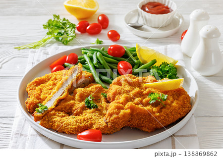 Breaded pork schnitzel with green beans and lemon Breaded pork schnitzel with green beans and lemon 138869862