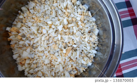 Chopped boiled eggs mixed with onions in a bowl on a checkered tablecloth Chopped boiled eggs mixed with onions in a bowl on a checkered tablecloth 138870003