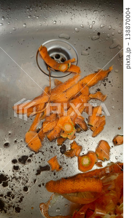 Carrot peels pile on a sink with water droplets during meal prep in a kitchen Carrot peels pile on a sink with water droplets during meal prep in a kitchen 138870004