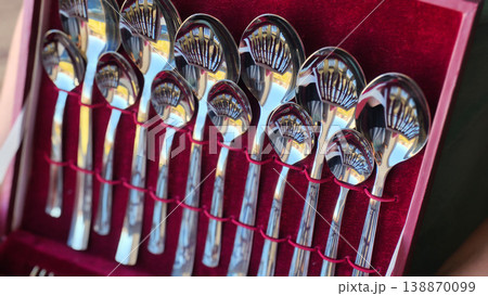 Set of stainless steel spoons displayed in a red velvet box indoors 138870099