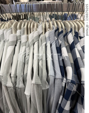 Stack of neatly arranged checkered and striped shirts on hangers in retail store background Stack of neatly arranged checkered and striped shirts on hangers in retail store background 138870205