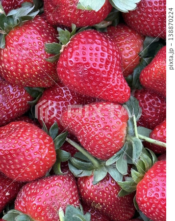 Fresh ripe strawberries with green leaves in close-up, vibrant red fruit background Fresh ripe strawberries with green leaves in close-up, vibrant red fruit background 138870224
