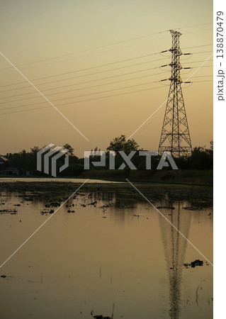 The steel high tower for supply the electricity with group of birds in the wetland and clear sunset sky in background 138870479